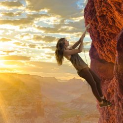 Woman climbing rope up cliff