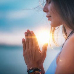 Young woman meditating with her eyes closed, practicing Yoga with hands in prayer position.